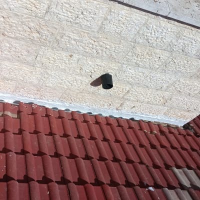 גג רעפים אדום עם קיר אבן לבן