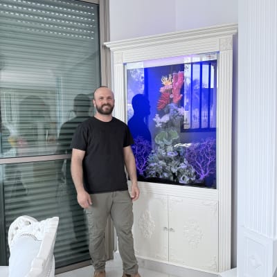 אדם עומד ליד אקווריום מעוצב בבית