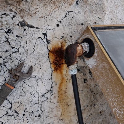 צינור חלוד עם מפתח צינורות על רצפה סדוקה