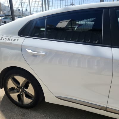 חלק אחורי של רכב לבן עם גלגל וסמל