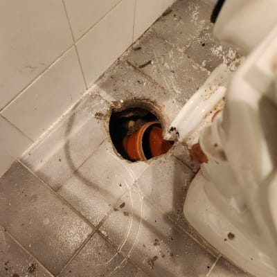 צינור כתום חשוף ברצפת חדר אמבטיה