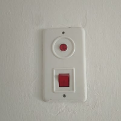 מתג חשמלי עם כפתור אדום על קיר לבן