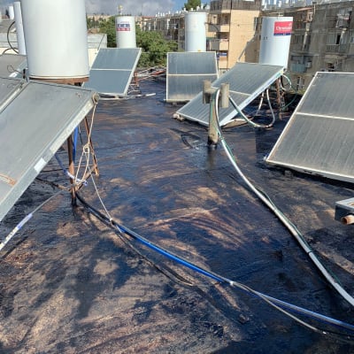 גג אטום בזפת עם קולטי שמש וצינורות