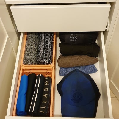 מגירה מאורגנת עם בגדים מקופלים וכובע