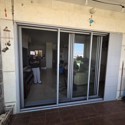 דלת הזזה מאלומיניום במרפסת עם השתקפות אדם