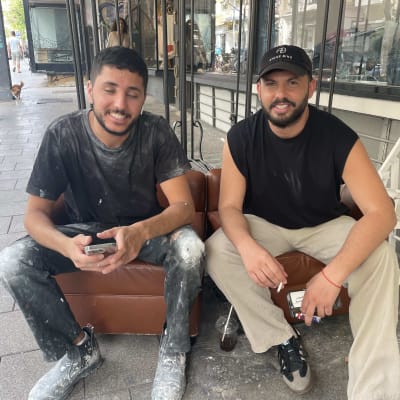 שני אנשים יושבים, אחד עם בגדים מוכתמים בצבע