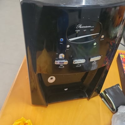 מכונת מים שחורה עם כפתורים, כפפות צהובות על שולחן