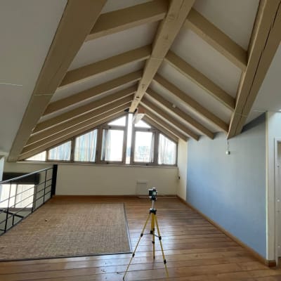 חדר עם קירות גבס, תקרה משופעת ומצלמה על חצובה