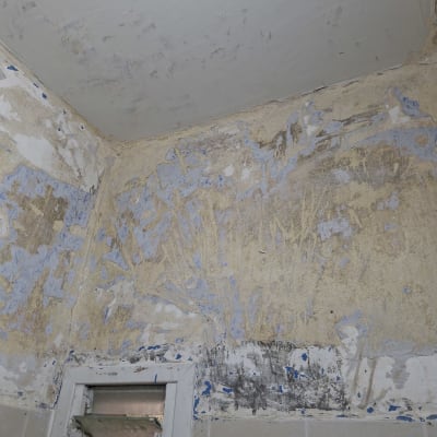 קיר עם סימני צבע ותיקונים, ללא אנשים או טקסט.