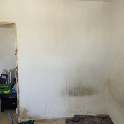 קיר עם סימני צבע נוזל, דלי ומברשת צביעה