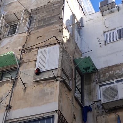 בניין ישן עם חלונות ותריסים, חוטים חשמליים גלויים