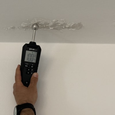 מד לחות נוגע בתקרה עם סימני רטיבות
