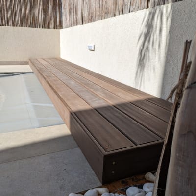 ספסל עץ ליד גדר במבוק ואבנים לבנות