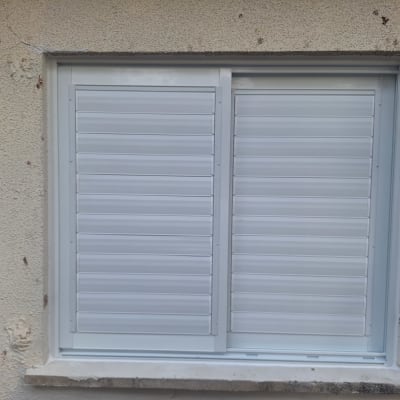 חלון אלומיניום עם תריסים סגורים בקיר חיצוני