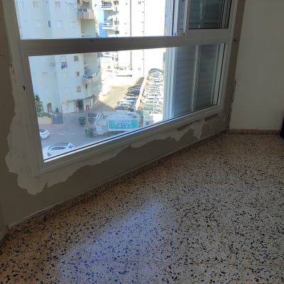 קיר עם תיקוני צבע ליד חלון גדול