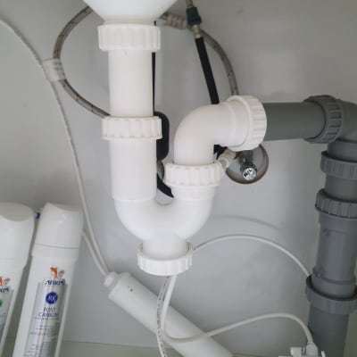 צנרת פלסטיק לבנה ואפורה מתחת לכיור