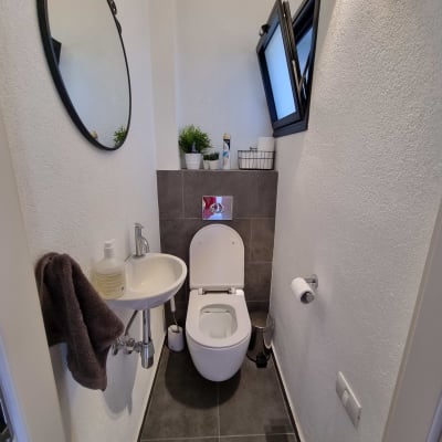 שירותים משופצים עם כיור קטן ומראה עגולה