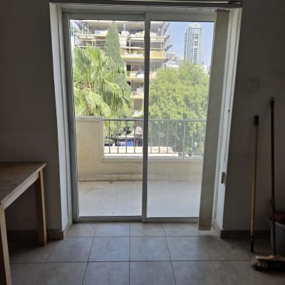 דלת זכוכית הזזה עם נוף חיצוני של עצים ובניינים