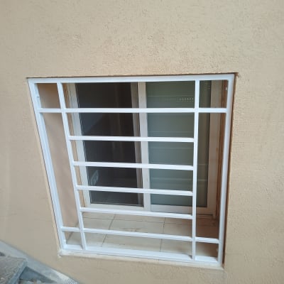 חלון עם סורגים לבנים על קיר חיצוני