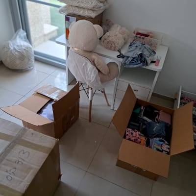 קופסאות קרטון פתוחות עם בגדים וחפצים על הרצפה