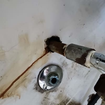 צינור חלוד מחובר לקיר עם חור