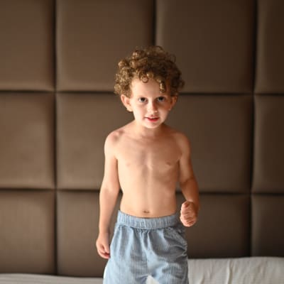 ילד עומד על מיטה עם רקע מרופד