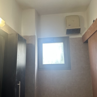 חדר אמבטיה עם חלון ומאוורר קיר