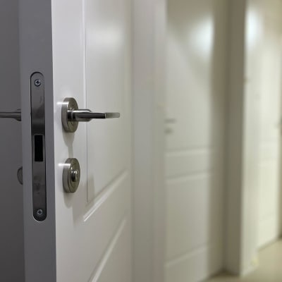 דלת לבנה עם ידית מתכת כסופה פתוחה מעט