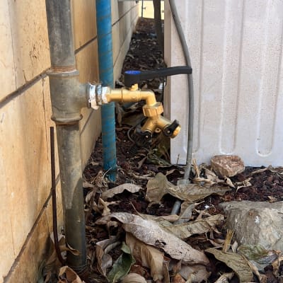 ברז מים מחובר לצינור ליד קיר חיצוני