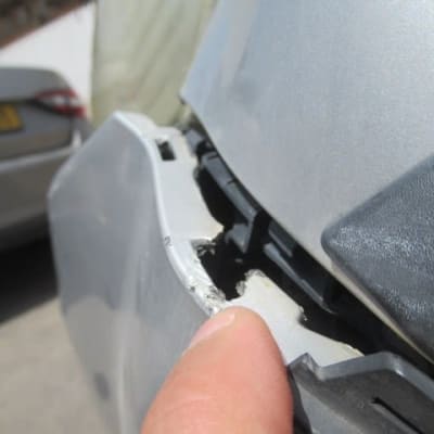 תקריב של פגוש רכב פגום עם אצבע מצביע