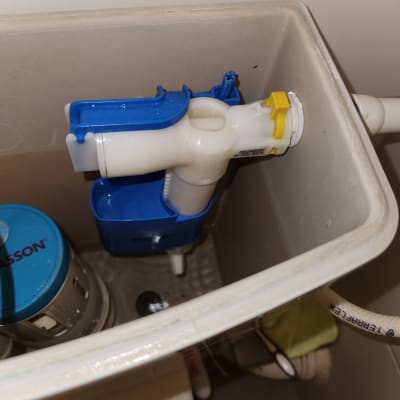 מנגנון פלסטיק כחול ולבן בתוך מיכל הדחה