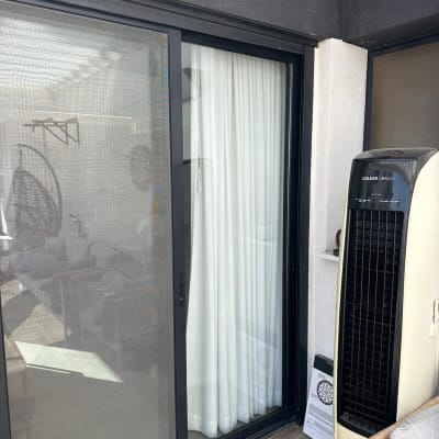 דלת זכוכית עם וילון לבן ומזגן נייד