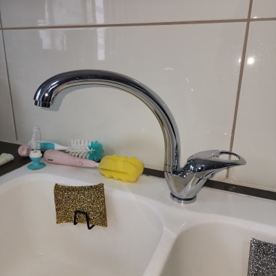 ברז כרום מעל כיור עם ספוגים ומברשות