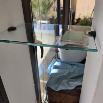מדף זכוכית שקוף מותקן על קיר עם תומכים שחורים