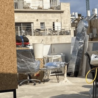 רהיטים עטופים בניילון על גג, מנוף ברקע