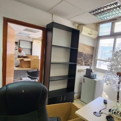 שני אנשים מסדרים משרד עם מדפים וציוד משרדי