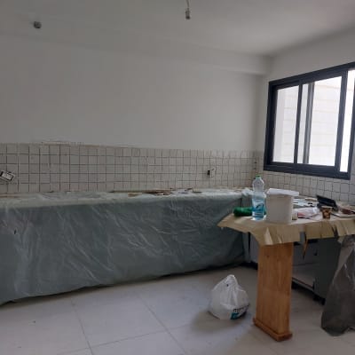 מטבח בשיפוץ עם כיסוי פלסטיק, כלים וחומרים על השיש