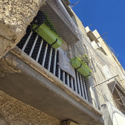 מרפסת עם רשת למניעת יונים על רקע שמיים כחולים