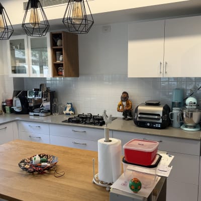 מטבח מודרני הכולל ארונות לבנים, אי עץ ומשטח עבודה מאובזר