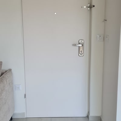 דלת לבנה עם ידית מתכת ובריח עליון