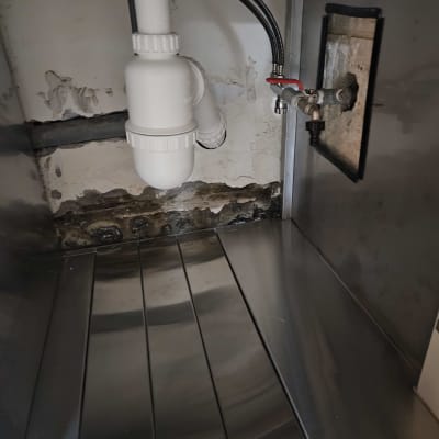 צנרת מתחת לכיור עם ברזים וצינורות