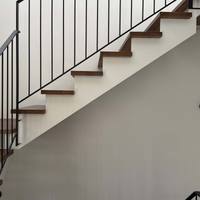 מדרגות עץ עם מעקה מתכת על קיר צבוע