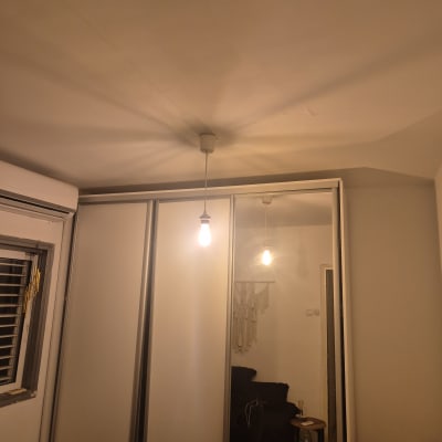 מנורה תלויה מהתקרה בחדר עם ארון ומראה