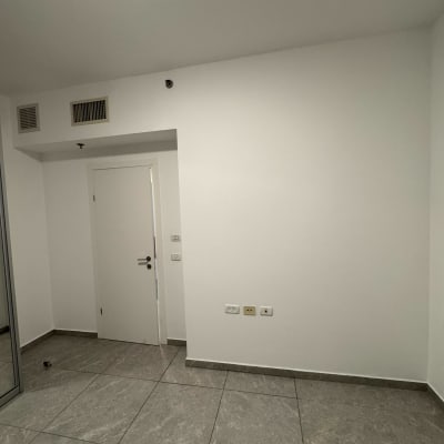 קיר צבוע ולבן עם דלת ורצפת אריחים אפורה