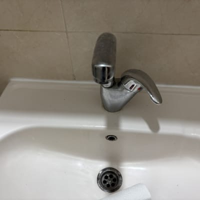 ברז כסוף מעל כיור לבן עם ניקוז