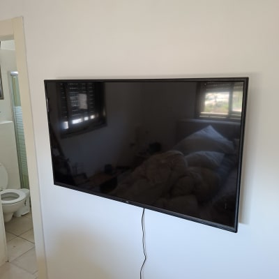 טלוויזיה תלויה על קיר בחדר שינה עם שירותים