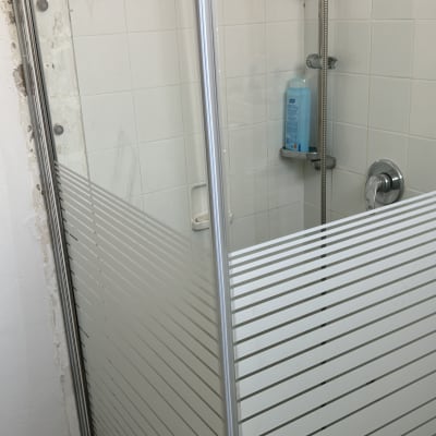 מקלחון זכוכית עם בקבוק שמפו על מדף