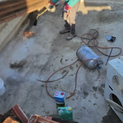 עובד מבצע עבודת איטום על גג עם ציוד מתאים