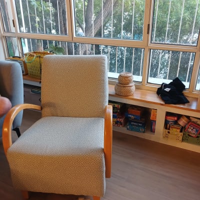 כיסא ליד חלון עם עציצים וספרים על מדף