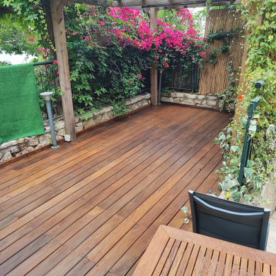 פרגולה מעץ עם צמחייה מטפסת ופרחים ורודים